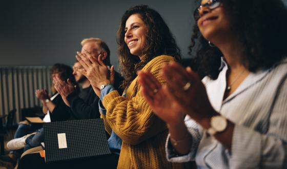 En gruppe tilhørere applauderer på seminar