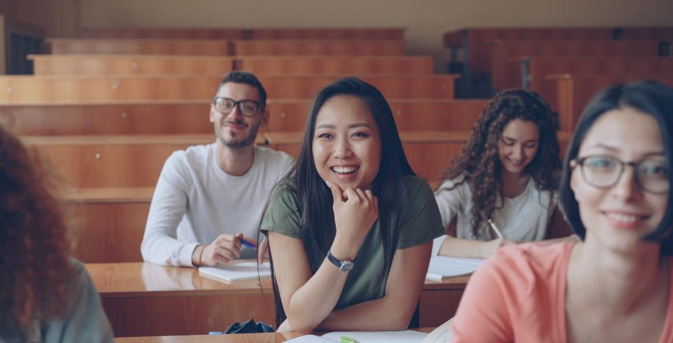 Smilende studenter sitter i et auditorium.