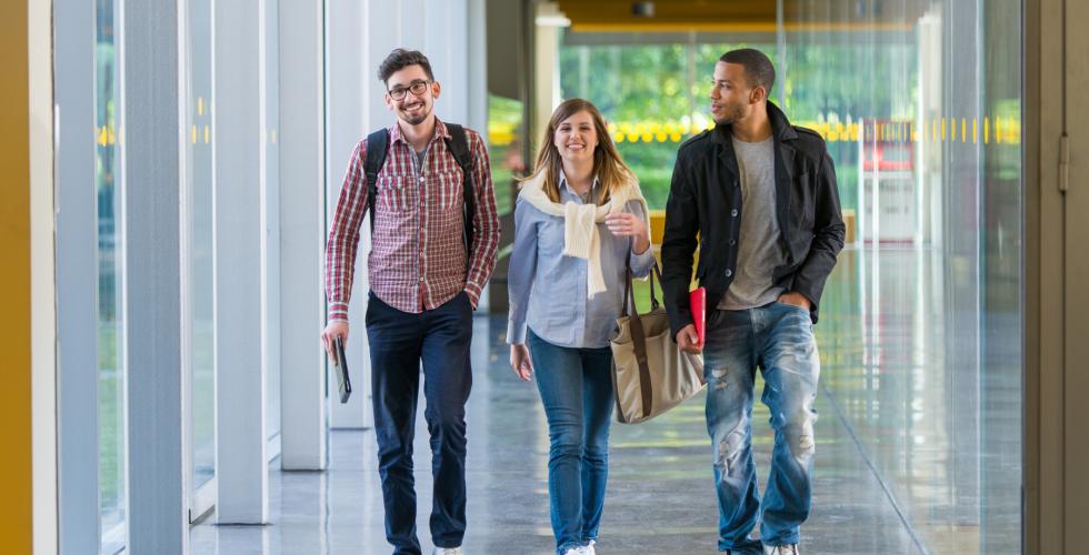 Tre studenter går nedover gangen på campus