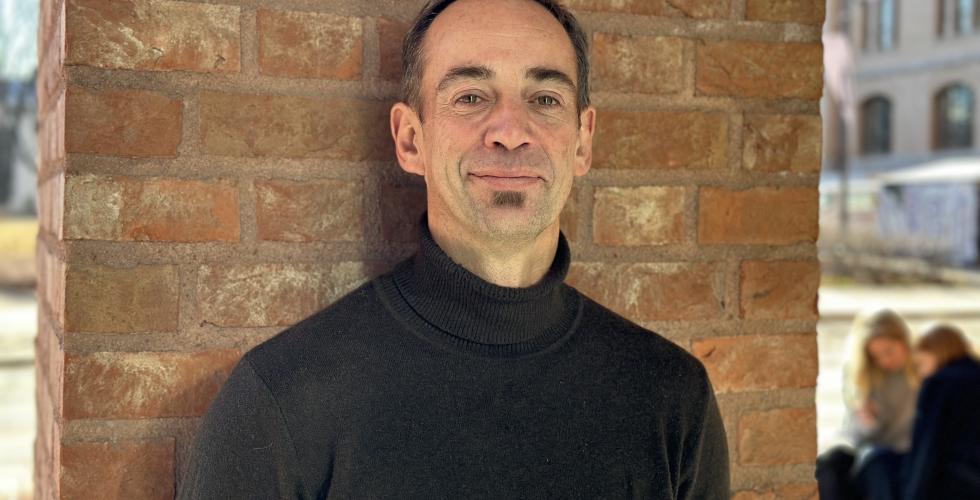 Portrett av Malcolm Langford mot en brun vegg